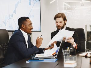 african-man-black-suit-international-partners-people-sitting-table-with-laptop