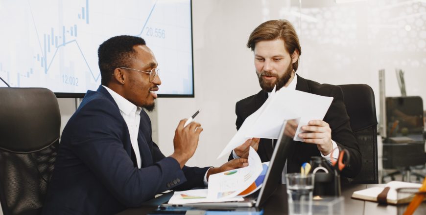 african-man-black-suit-international-partners-people-sitting-table-with-laptop