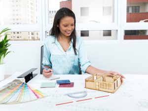 smiling-african-american-lady-chair-taking-notes-near-plan-model-house-table (1)